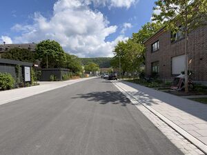 Neu angelegte Straße, links Wohnhäuser, rechts eine Kita im Backsteingebäude