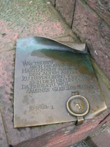 Schild beim Brückenaff in Heidelberg mit der Inschrift: WAS THUSTU / MICH HIE ANGAFFEN / HASTU NICHT GESEHEN / DEN ALTEN AFFEN / ZU HEYDELBERG / SICH DICH HIN UNND HER / DA FINDESTU WOL / MEINES GLEICHEN MEHR